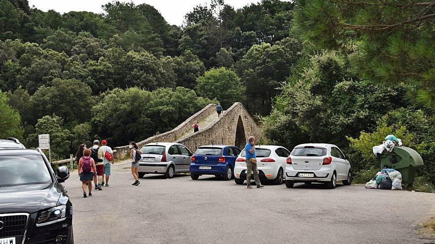 Visitants davant del pont de Pedret a la petita zona d&#039;aparcament que hi ha, i el contenidor curull, ahir