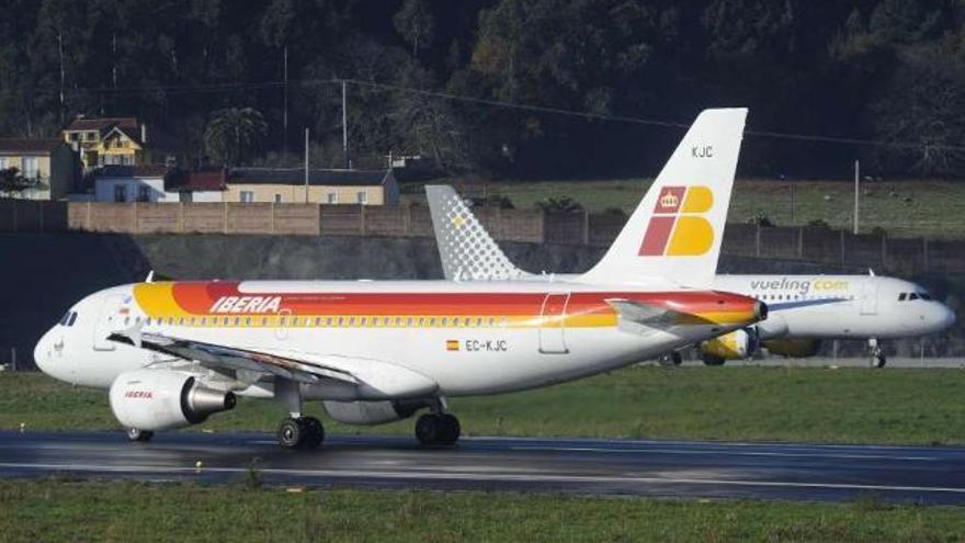 Un avión de la compañía Iberia y otro de Vueling, en el aeropuerto de Alvedro. / fran martínez