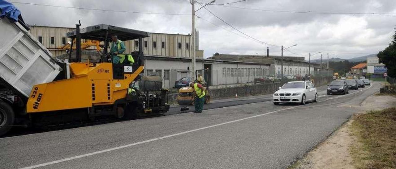 Los coches circulan en caravana por el carril que dejan libre los trabajos de asfaltado.