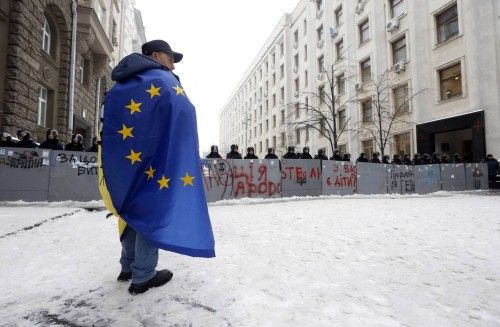 Demonstrator in favour of Ukraine's integration with EU stands with an EU flag draped over his shoulders in front of Interior Ministry personnel blocking a street in central Kiev