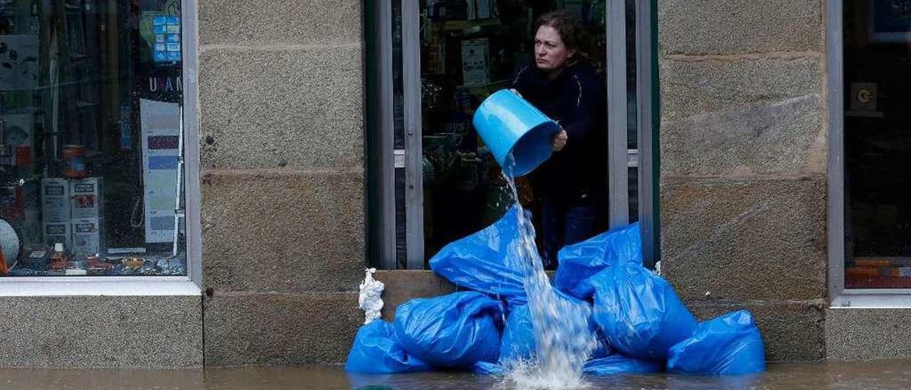 Una mujer achica agua de su negocio en Gondomar por las inundaciones del año pasado. // R. Grobas