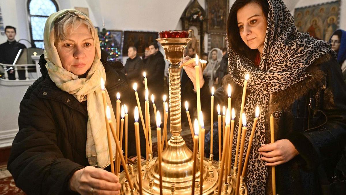 Dos mujeres encienden velas en una iglesia de Kiev el pasado 25 de diciembre, durante la celebración de la Navidad.