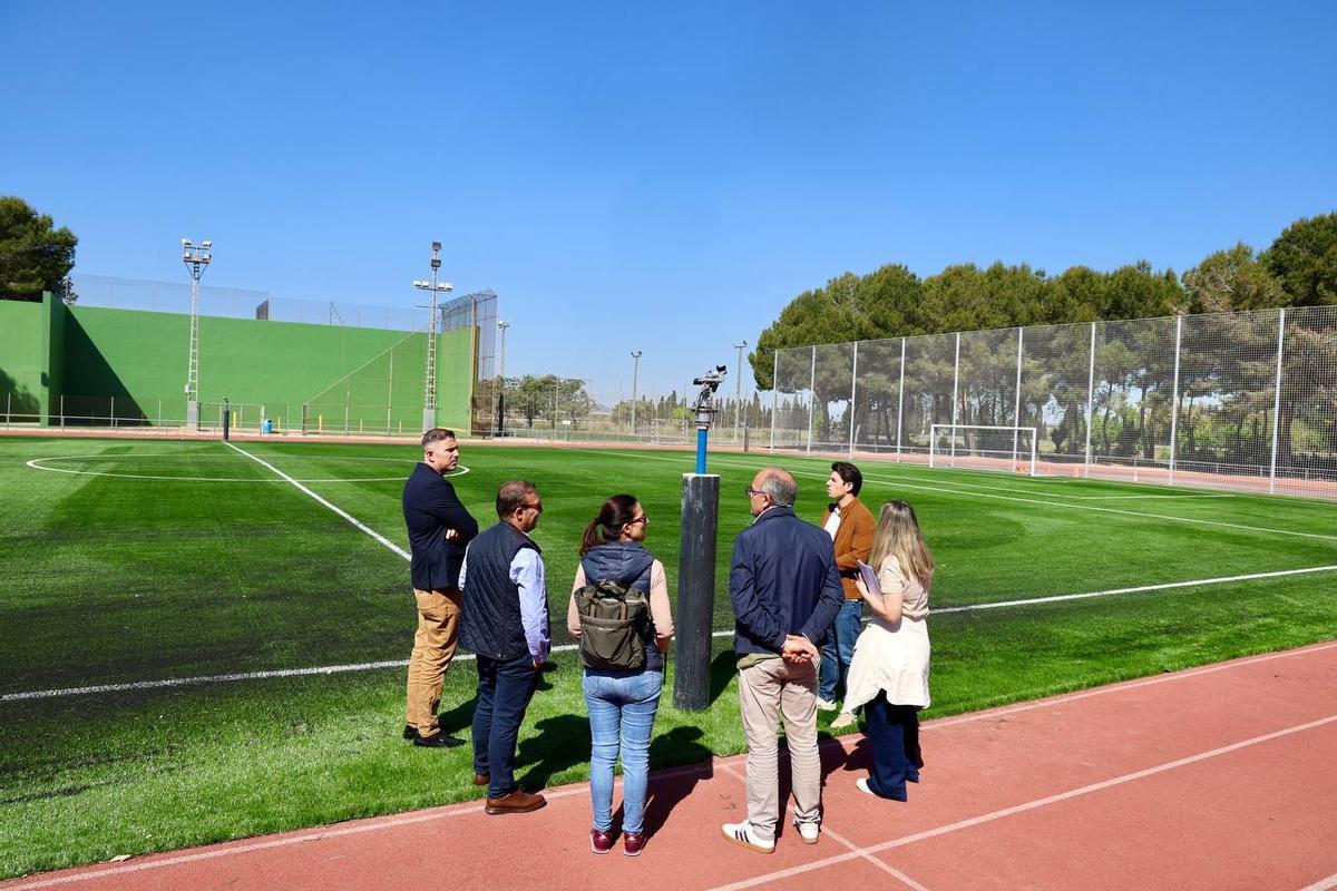 Las autoridades observan el renovado campo de césped artificial en el polideportivo de Cullera y el sistema de riego.