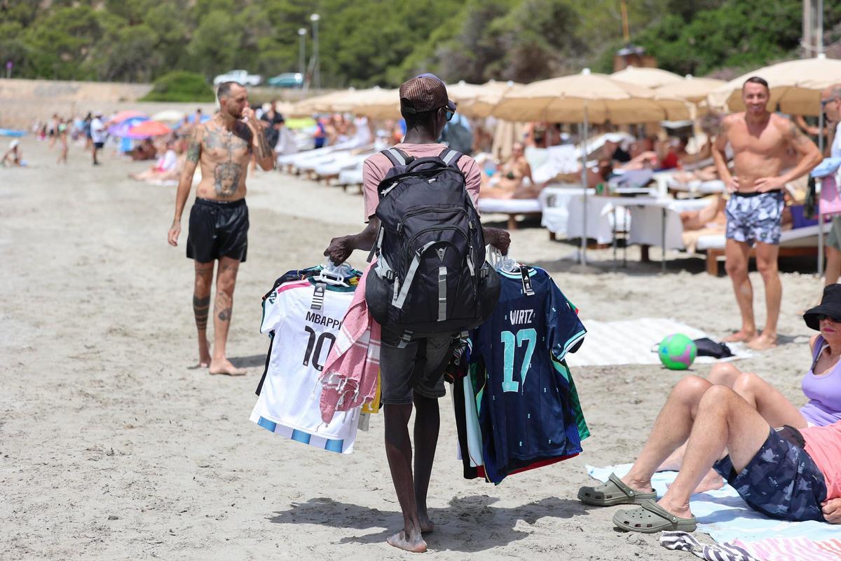 Un vendedor ofrece camisetas de selecciones de fútbol a los turistas