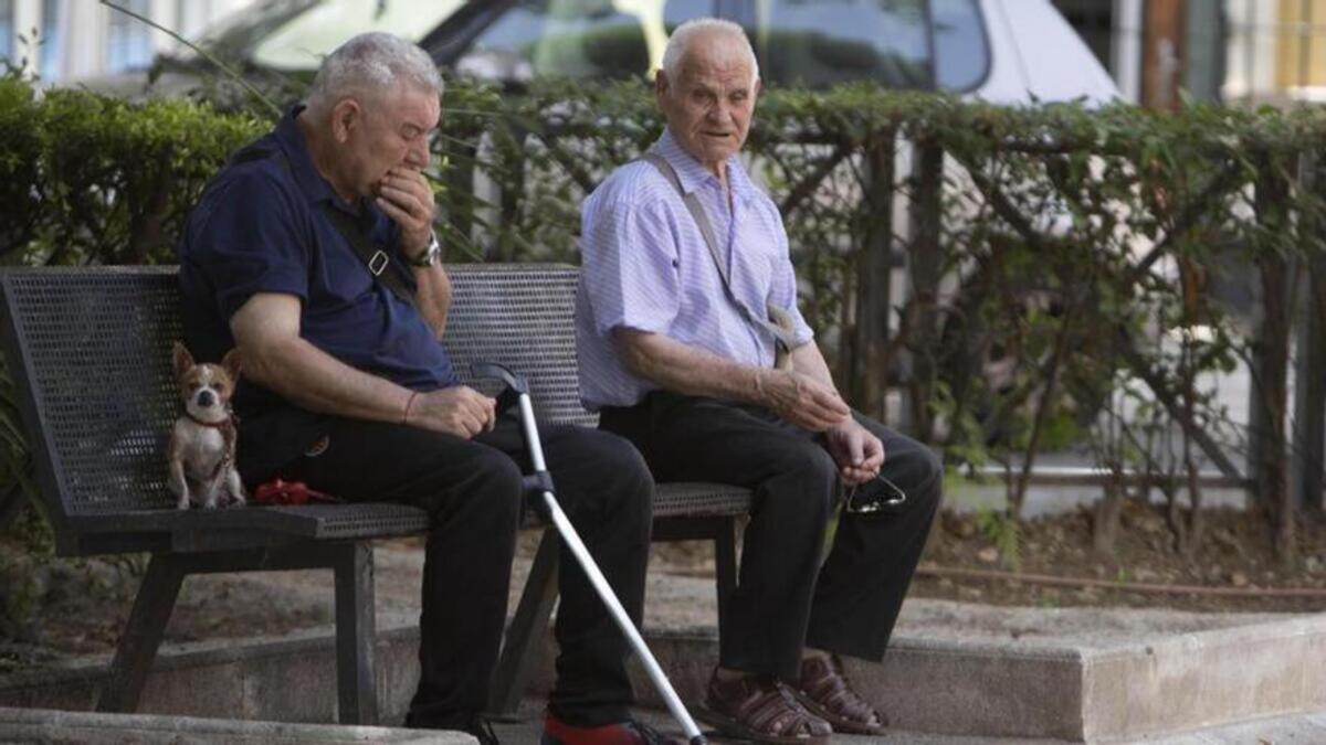 Dos pensionistas sentados en un banco del parque.