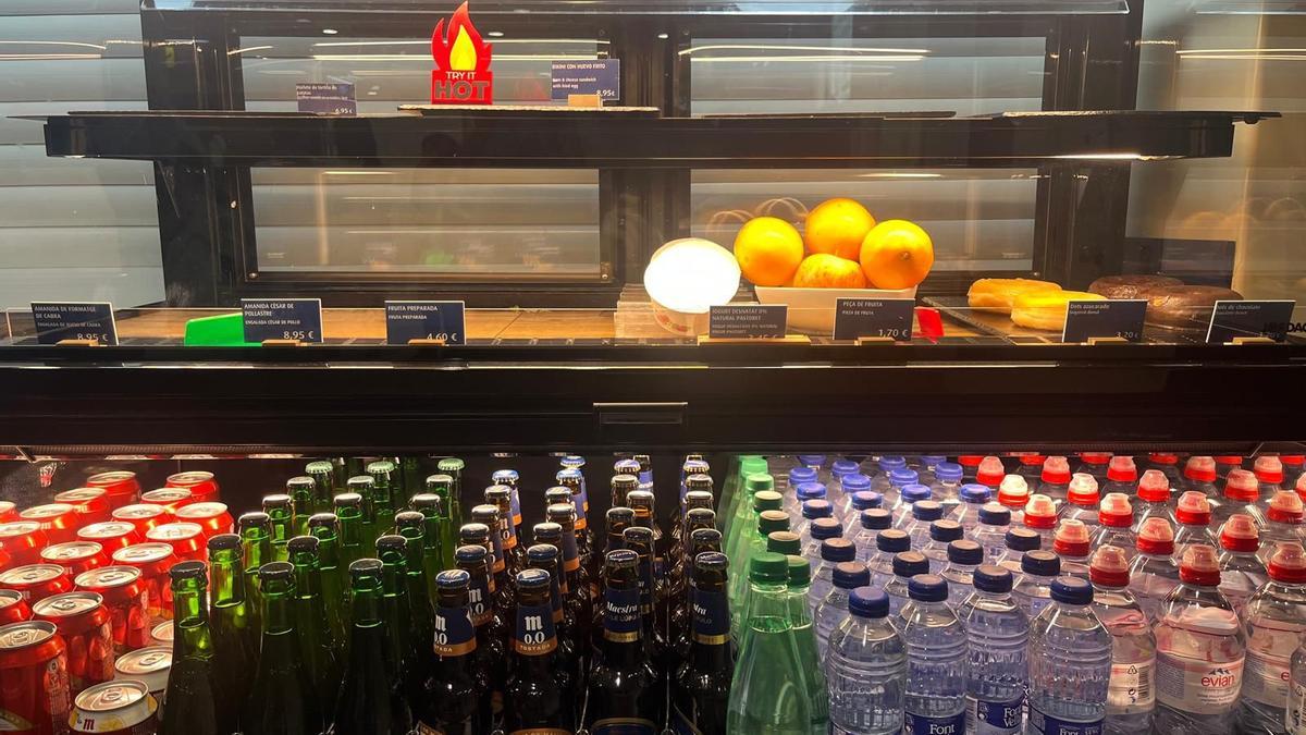 Detalle de una nevera a con productos de la cafetería, con los carteles en catalán y castellano.