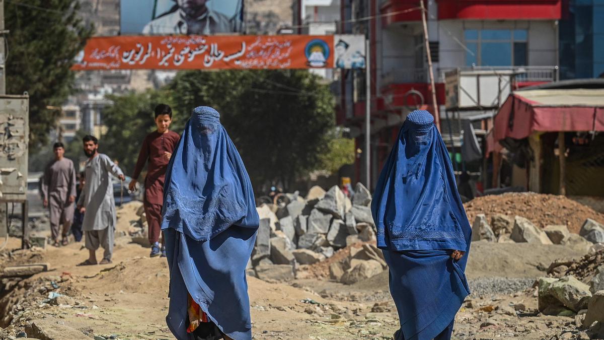 Dos mujeres con burka caminan por una calle con escombros en Kabul.