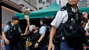 La policía detiene a una mujer con flores en el centro Hong Kong en el 34 aniversario de la represión de la Plaza Tiananmen de Beijing en 1989, cerca de donde se suele realizar la vigilia con velas en la antigua colonia británica. 