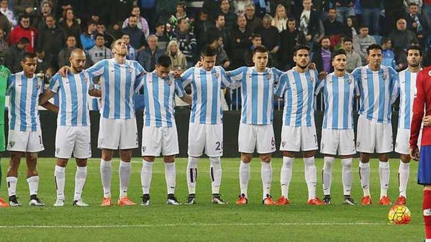 Los jugadores del Málaga CF guardan un respetuoso minuto de silencio antes de comenzar el duelo contra el Atlético, que se saldó con triunfo malaguista.