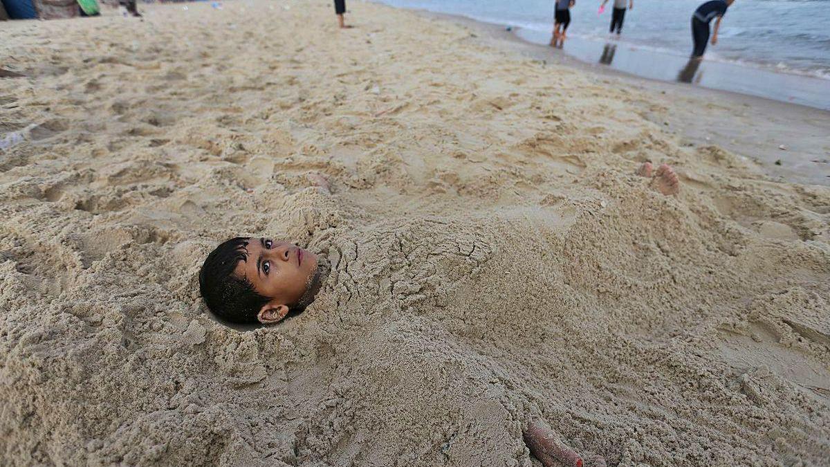 Un niño palestino se relaja en la playa en el sur de Gaza tras salir de las restricciones por el Covid.