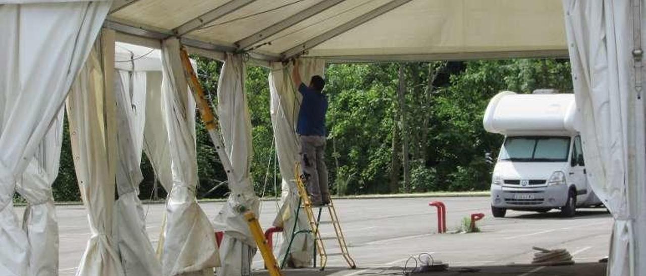 Operarios instalando una carpa en el aparcamiento de Arenas.