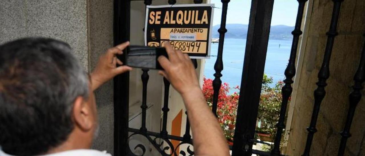 Un hombre fotografía un cartel que anuncia un apartamento en alquiler en Sanxenxo. // GUSTAVO SANTOS