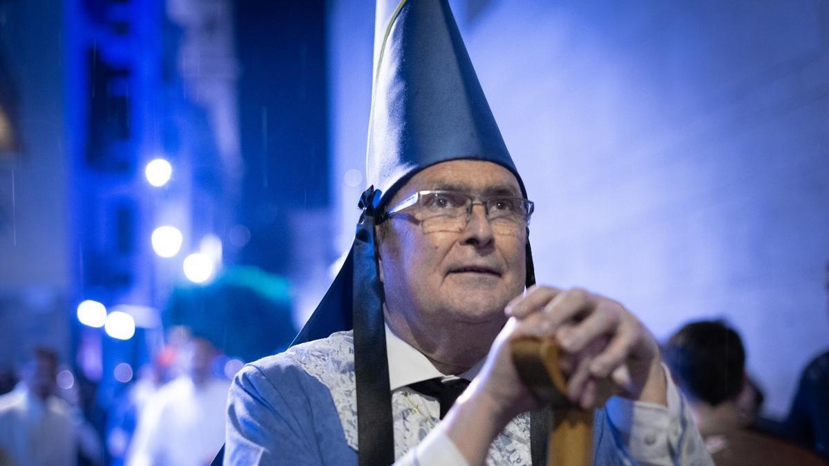 José Ballesta, bajo lluvia, mira al Cristo del Amparo durante la procesión del Viernes de Dolores de 2025