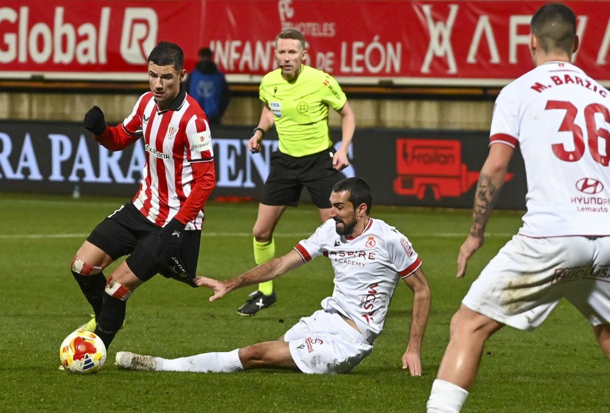El centrocampista del Athletic Club, Mikel Jauregizar (i), se lleva el balón ante el jugador de la Cultural Leonesa durante el encuentro correspondiente a los octavos de final de la Copa del Rey que disputaron hoy martes la Cultural Leones y Athletic Club en el estadio Reino de León. EFE / J. Casares
