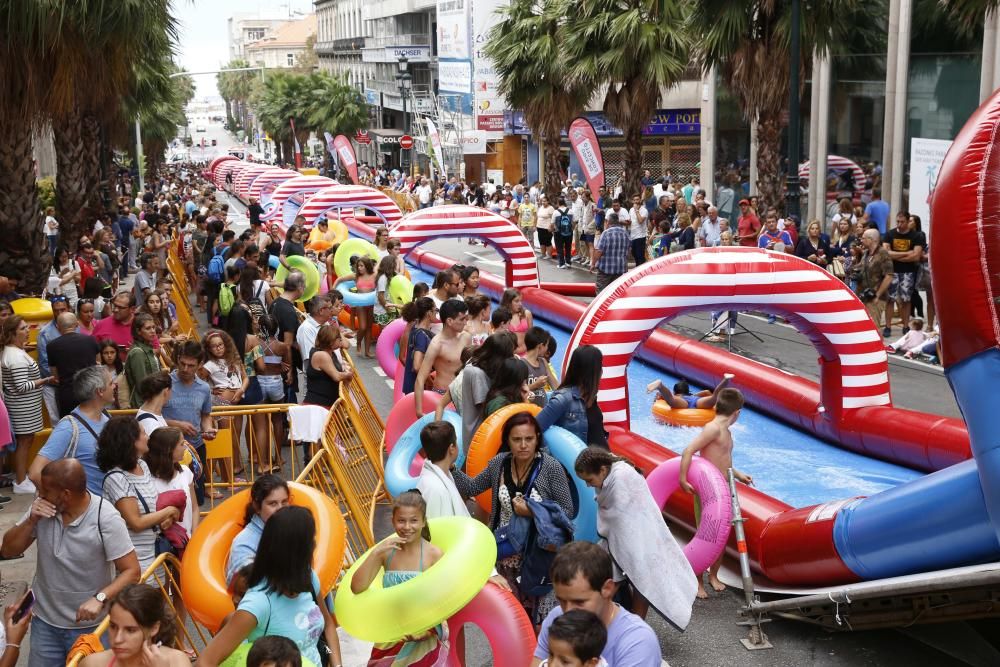 Cientos de personas disfrutan del tobogán acuático en la calle Colón