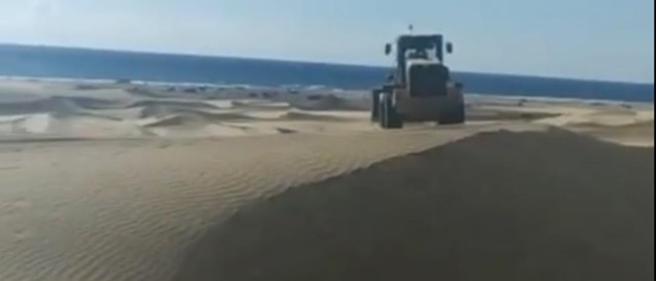 Un tractor retira la arena que se acumula en los muros del Paseo Costa Canaria, en Playa del Inglés (3/05/2021)