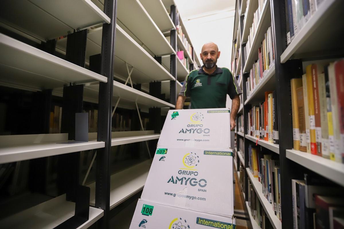 Un operario retira libros empaquetados de las estanterías semivacías en Amador de los Ríos.