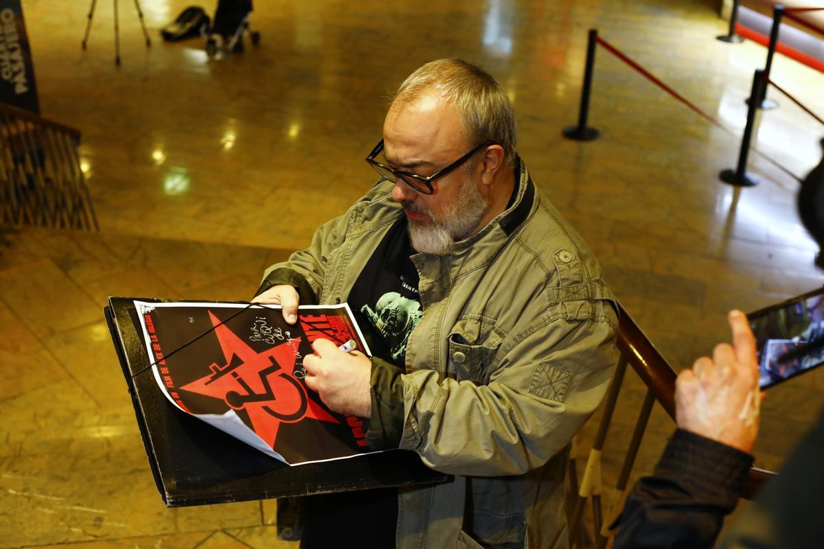 Álex de la Iglesia le firma un cartel de 'Acción mutante' a un fan.