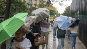 Personas andando por la calle con paraguas