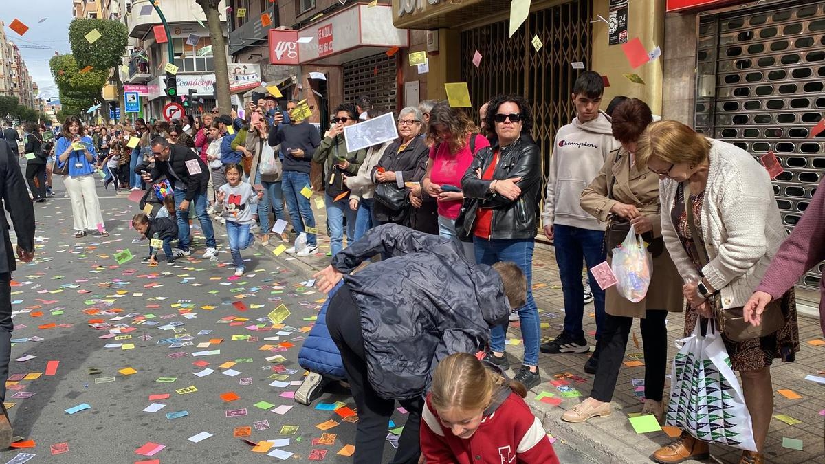 Vecinos recogen las estampitas de colores durante el paso de la procesión