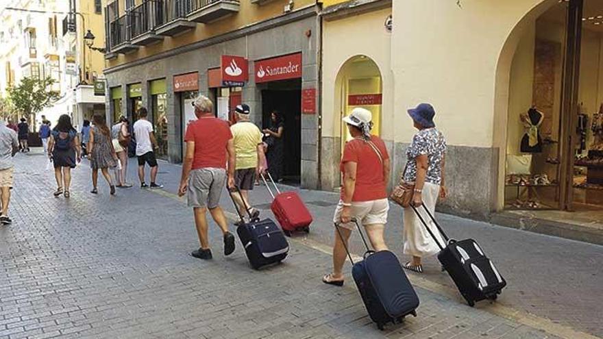 Varios turistas cruzan con sus maletas la peatonal calle Sant Miquel, en el casco antiguo, donde está prohibido el alquiler vacacional en pisos.
