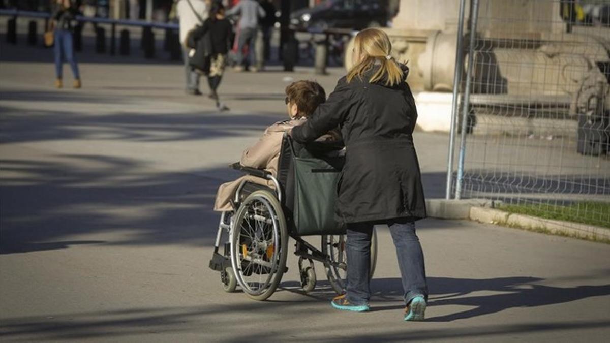 Una persona en silla de ruedas, acompañada de una cuidadora, en Barcelona