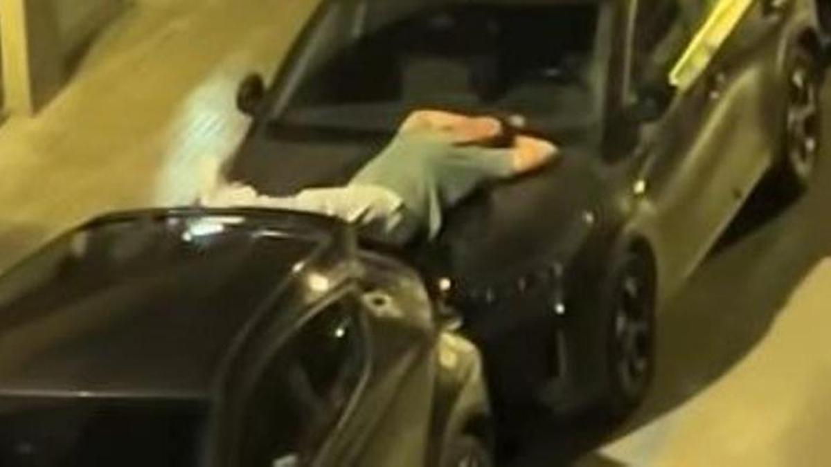 Un hombre dormido en el capó de un coche