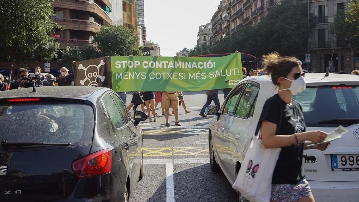 Miembros de Eixample Respira despliegan una pancarta contra la contaminación en la calle de Aragó, esta tarde