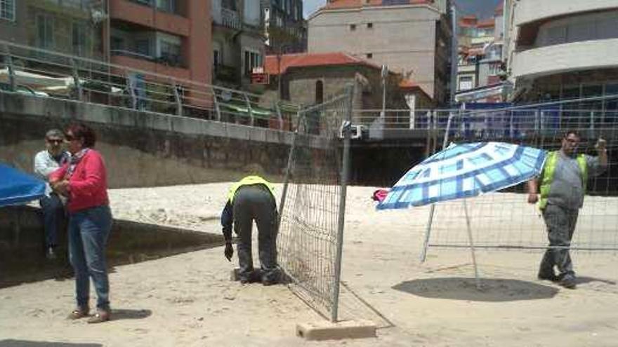 Los operarios instalan el vallado en la playa.