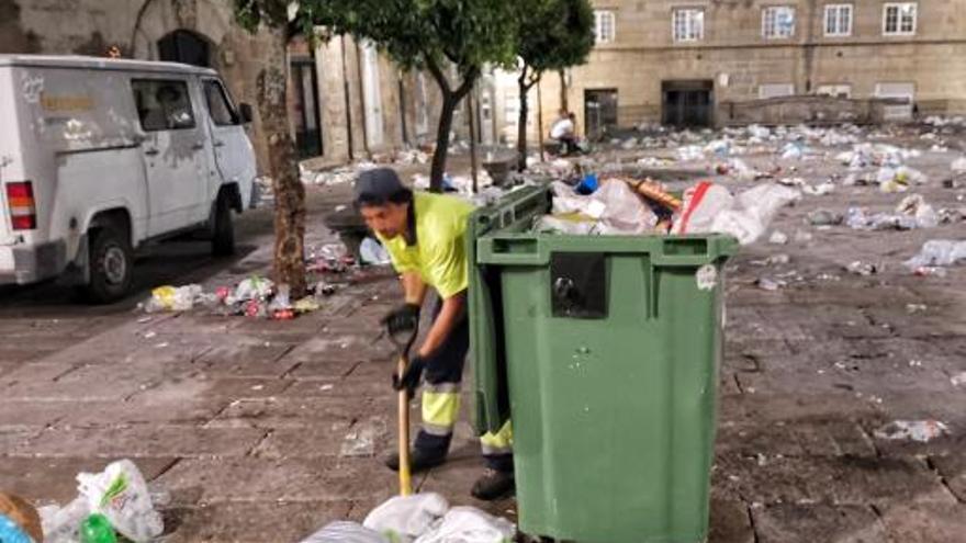 Un operario limpia la basura generada por las peñas en la Praza do Teucro.