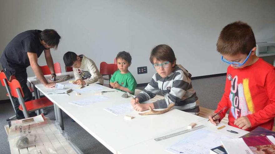 Arriba, los niños Pedro Blanco, Iván González, Teo Llaneza y Darío Sánchez junto al monitor, Rubén Fernández, clasificando las piezas. A la izquierda, varias familias excavan en el yacimiento riosellano.