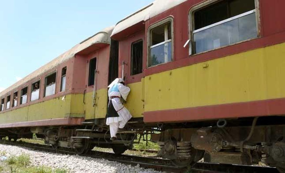 Una dona puja a un tren en marxa a Albània.