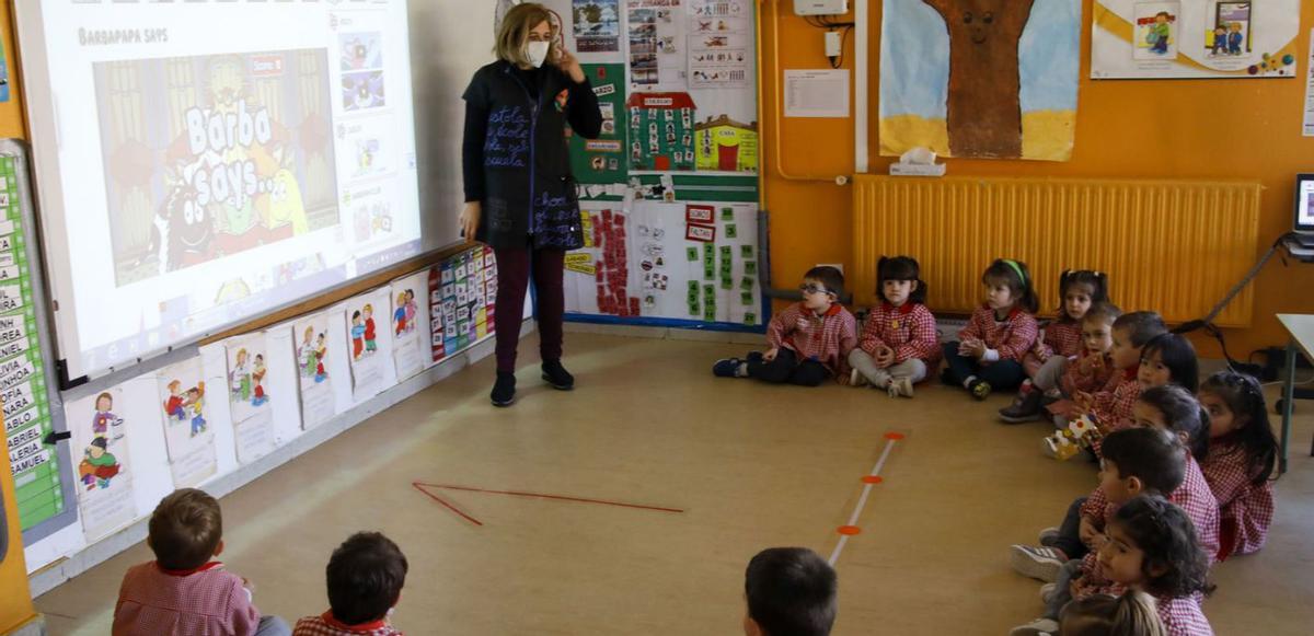 Arriba, la directora del centro, Yolanda Camello, junto con varios alumnos usando una pizarra digital. Sobre estas líenas, a la izquierda, Nerea Suárez, Martina Álvarez, Edel Garcés, Emily Monzón y Daniel Tuero realizando una manualidad; a la dercha, Joshua Eghosa y Valeria Victoria Chancayauri junto a su profesora, Alma González. | Marcos León