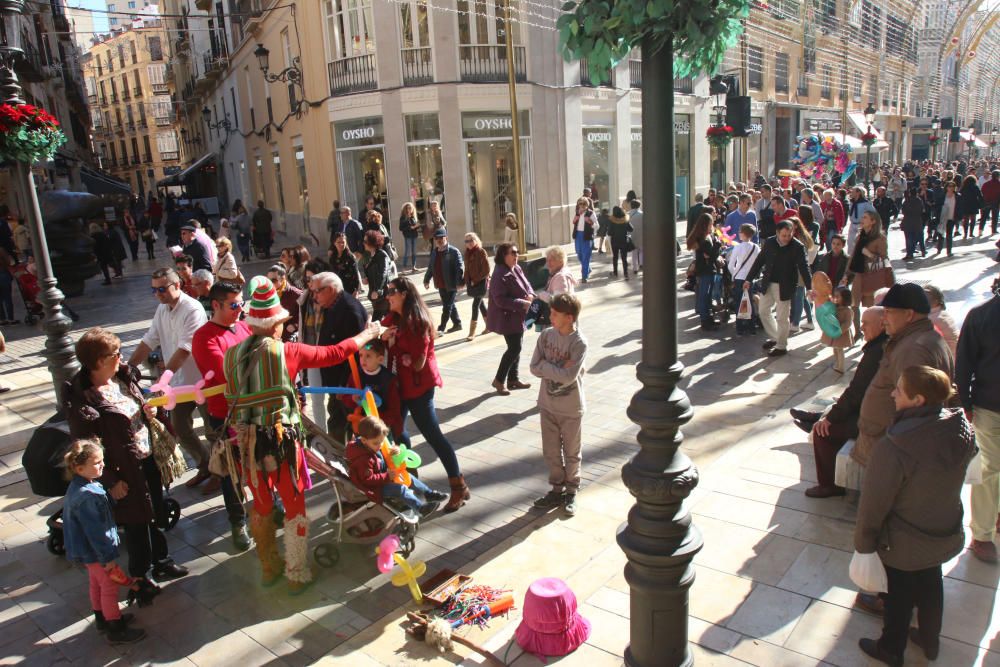 Muchos malagueños y turistas aprovechan el buen tiempo y el día festivo por la Inmaculada Concepción para pasear y realizar las compras navideñas en el Centro de Málaga.