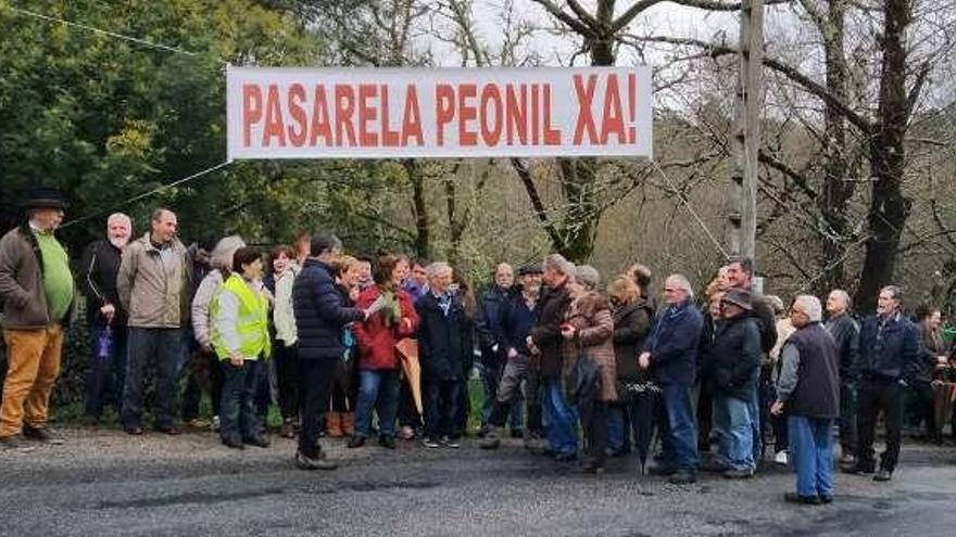 Vecinos con pancarta reivindicativa en el puente del río Pacín. // FdV