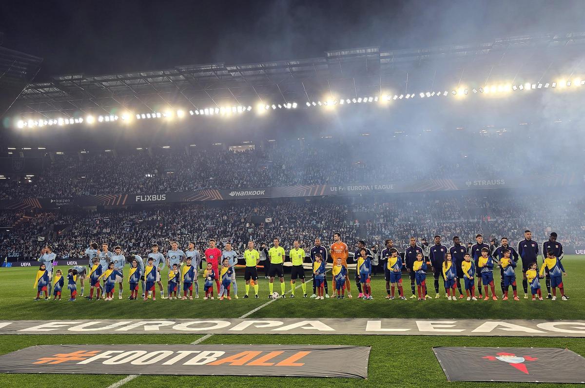 Los jugadores del Celta de Vigo y del Olympique de Lyon antes del inicio del partido con la grada de Río de fondo.