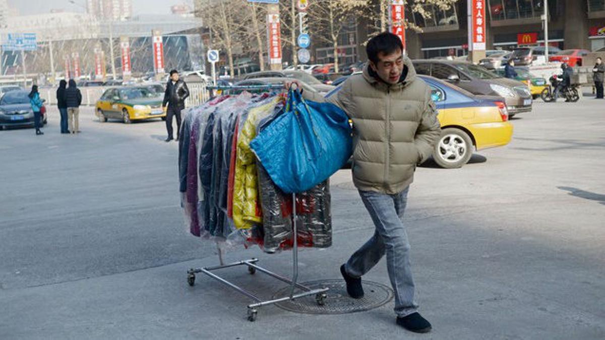 Un hombre transporta vestidos en una calle de Pekín.