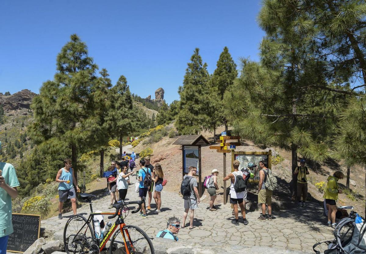 Excursionistas en el inicio del sendero de subida al Roque Nublo, al fondo de la imagen.