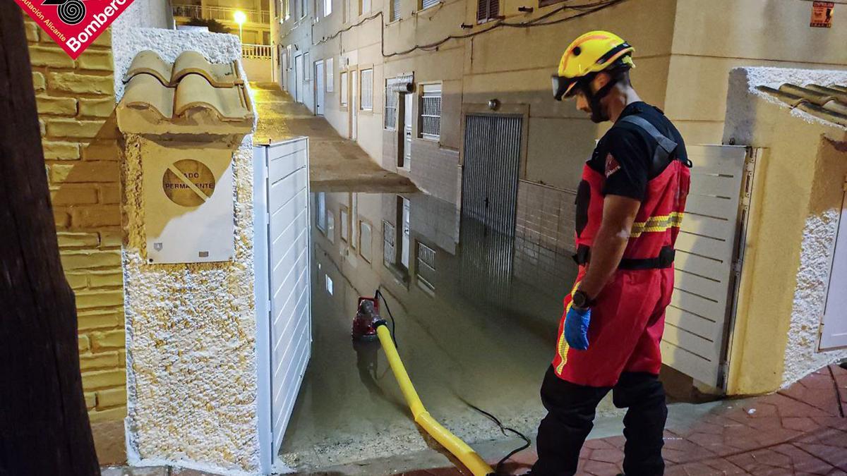 Un bombero achicando anoche el agua en un garaje inundado por la lluvia en Guardamar.