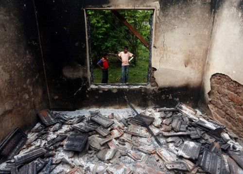 Muslim boys stand next to a burnt house after clashes between Buddhists and Muslims in Aluthgama