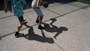 Dos niños jugando a baloncesto en un campamento de verano.