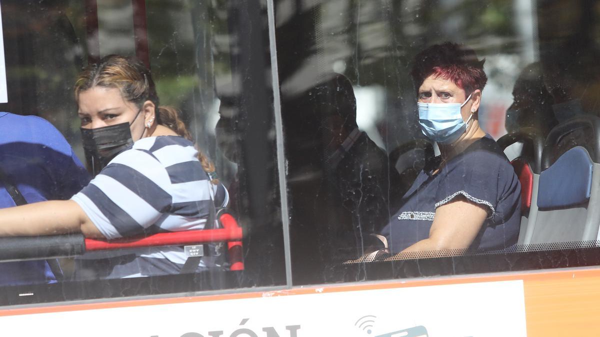 Dos mujeres portan la mascarilla correctamente en el transporte público.