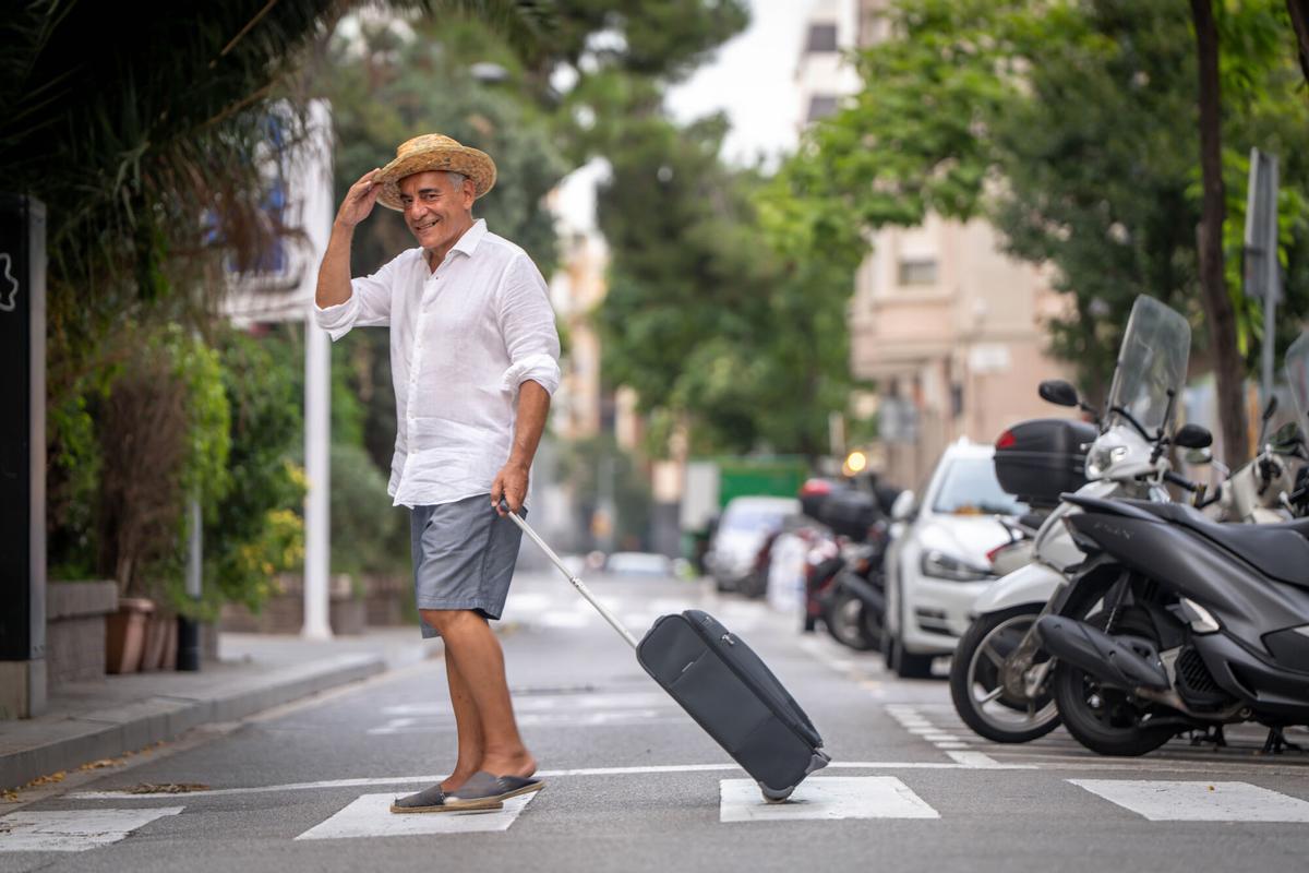 Un hombre que se va de viaje lleva una maleta por Barcelona.