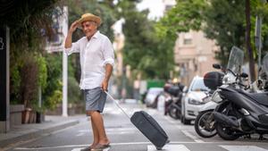Un hombre que se va de viaje lleva una maleta por Barcelona.