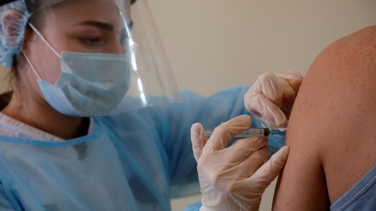 Una mujer sanitaria pone una vacuna contra el COVID a un paciente.