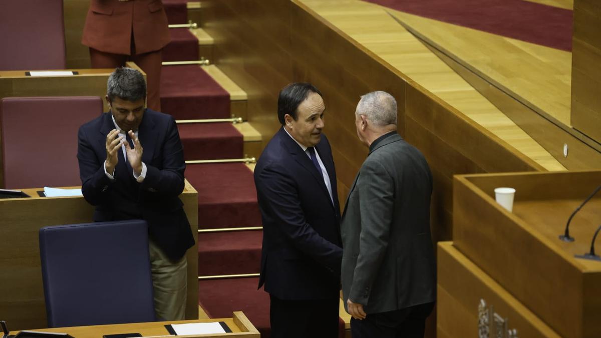 Llorca recibe la felicitación de Baldoví, ante un Mazón cabizbajo.