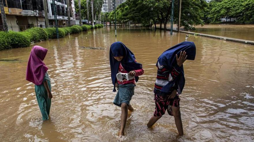 Tres niñas caminan sobre las calles inundadas de Yakarta.