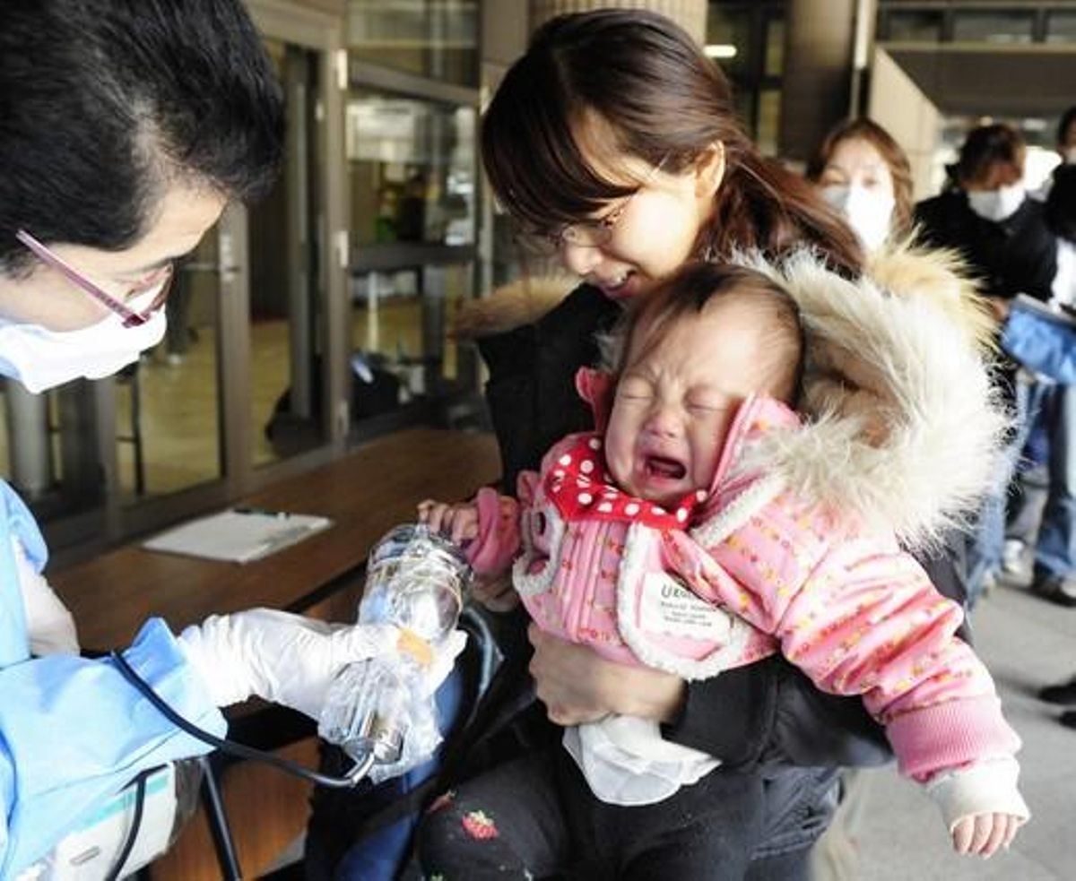 Una mare i el seu fill són escanejats per avaluar els seus nivells de radiació abans d’entrar en un dels centres d’evacuació de Fukushima.
