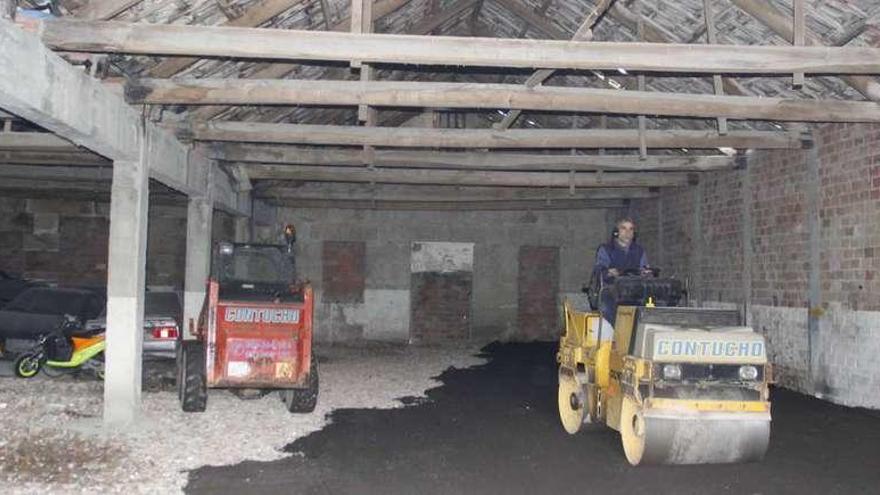 Trabajadores de una empresa contratada por el Concello, pavimentando el interior de una de las naves de Ojea. // Santos Álvarez