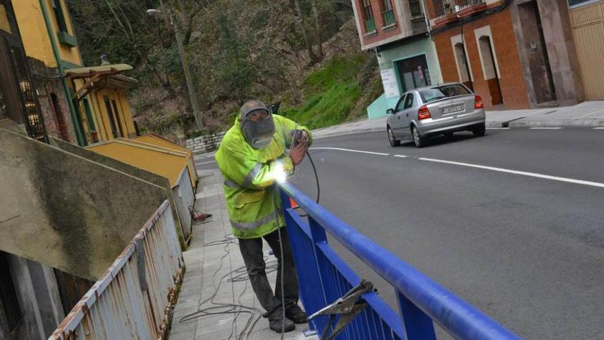 Un operario instala una valla de seguridad en la avenida de Sama, en Mieres.